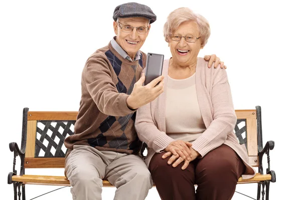 Seniors sitting on a bench and taking a selfie — Stock Photo, Image