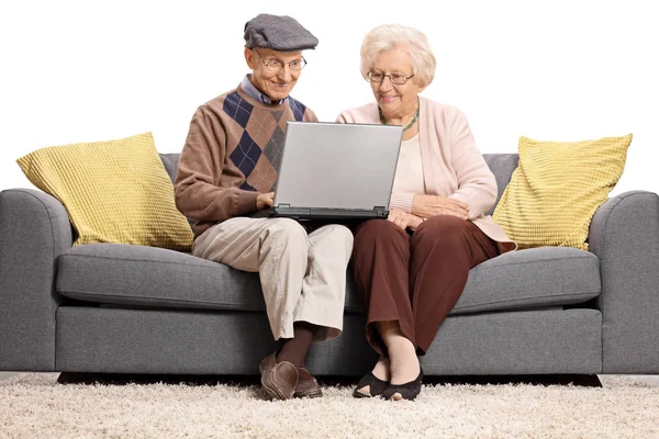 Пожилые люди сидят на диване и пользуются ноутбуком — стоковое фото