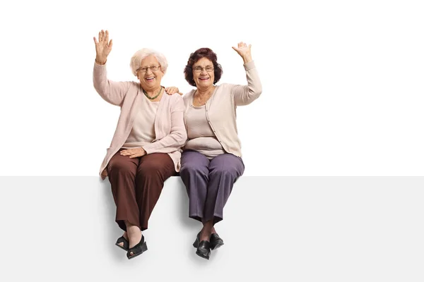 Mature women sitting on a panel and waving — Stock Photo, Image