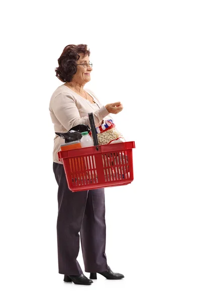 Пожилая женщина с корзиной для покупок ждет в очереди — стоковое фото