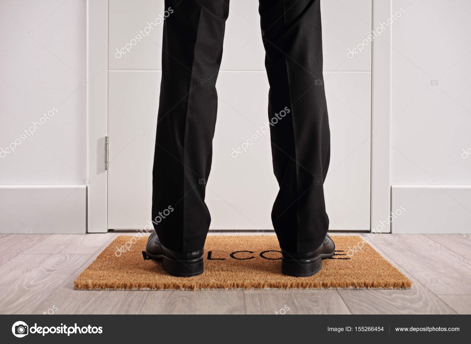 Person standing on a doormat in front of closed door Stock Photo by