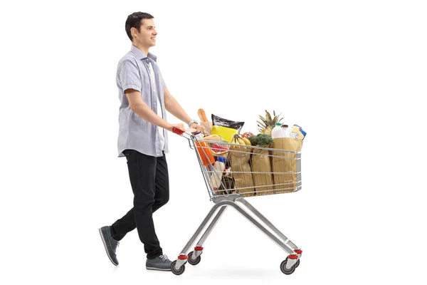 Hombre empujando un carrito de compras lleno de comestibles —  Fotos de Stock