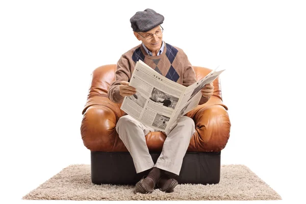 Homme assis dans un fauteuil et lisant un journal — Photo