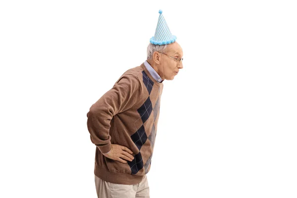 Elderly man with a party hat blowing with his mouth — Stock Photo, Image