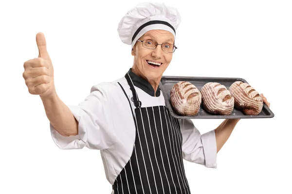 Baker holding with loaves of bread making thumb up sign — Stock Photo, Image