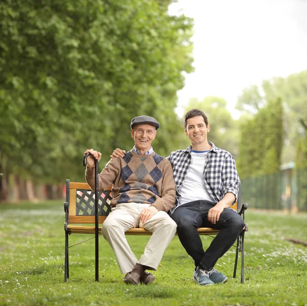 祖父和他的孙子在公园里的长椅上坐着 — 图库照片