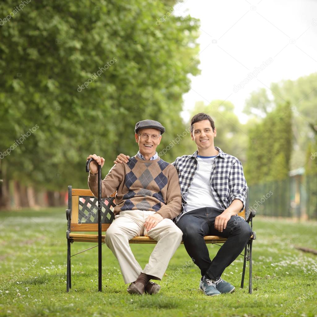 Grandfather with his grandson sitting on bench in the park