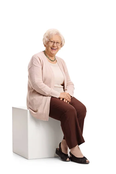 Elderly woman seated on a cube — Stock Photo, Image