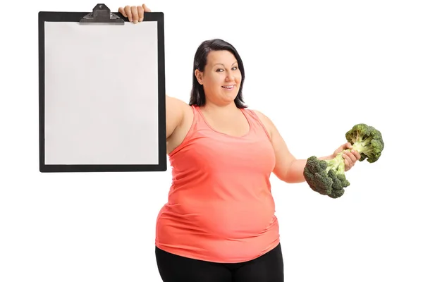 Woman holding a blank clipboard and a broccoli dumbbell — Stock Photo, Image