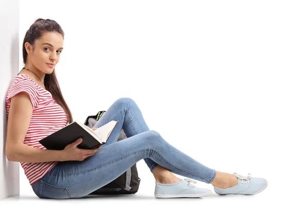 Kvinnliga tonåriga student med en bok som sitter på golvet — Stockfoto