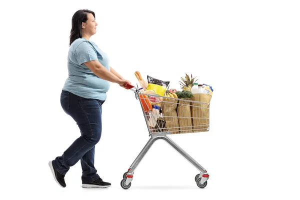 Mujer empujando un carrito lleno de comestibles — Foto de Stock