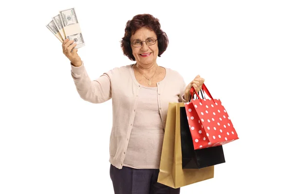 Rijpe vrouw met bundels van geld en boodschappentassen — Stockfoto