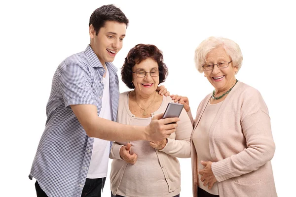 Man visar något på telefon till äldre kvinnor — Stockfoto