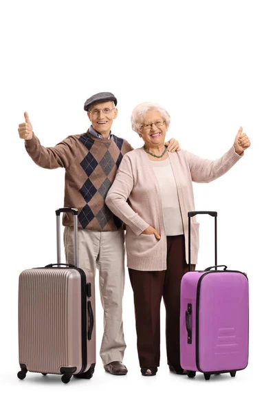 Пожилые люди с чемоданами, держащими большие пальцы вверх — стоковое фото