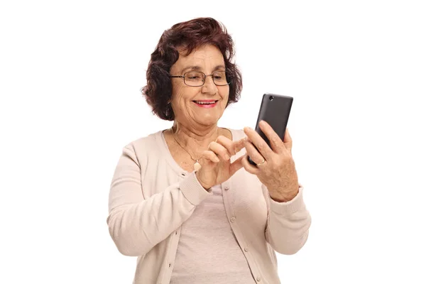 Ηλικιωμένη γυναίκα χρησιμοποιώντας ένα τηλέφωνο και χαμογελαστός — Φωτογραφία Αρχείου