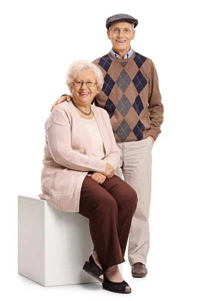 Woman sitting on cube with man standing — Stock Photo, Image