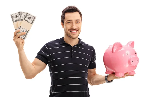 Hombre sosteniendo paquetes de dinero y una hucha —  Fotos de Stock