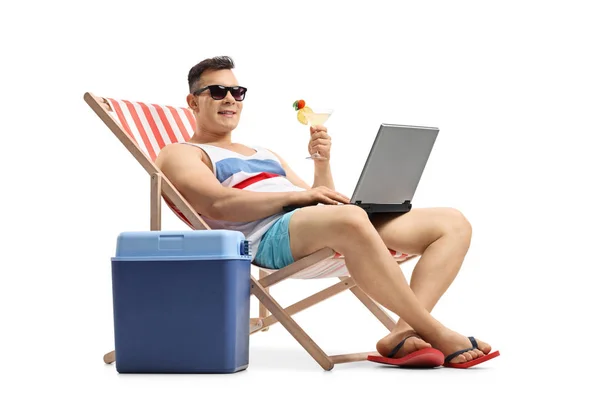 Homem com laptop e coquetel sentado em uma cadeira de praia — Fotografia de Stock