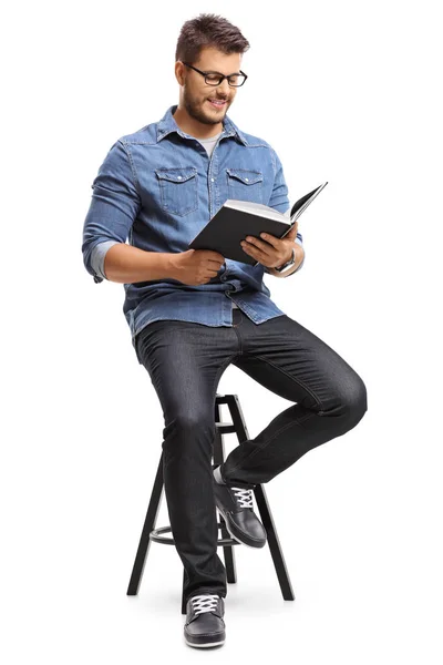 Kille sitter på en stol och läser en bok — Stockfoto
