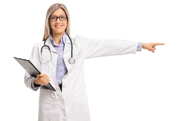 Жінка-лікар тримає буфер обміну і вказує праворуч — стокове фото