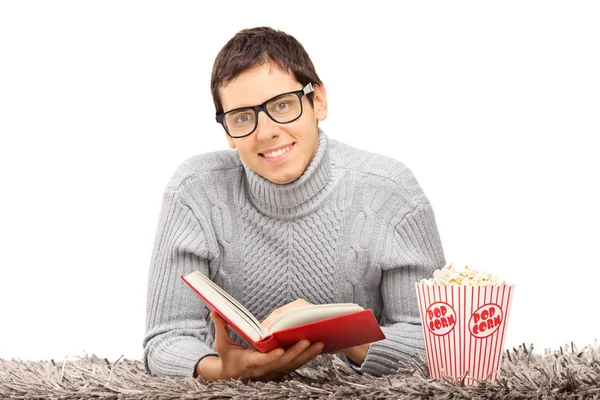 Strebertyp mit Buch und Popcorn — Stockfoto