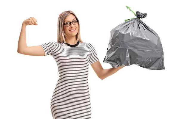 Woman flexing her biceps and holding a garbage bag — Stock Photo, Image