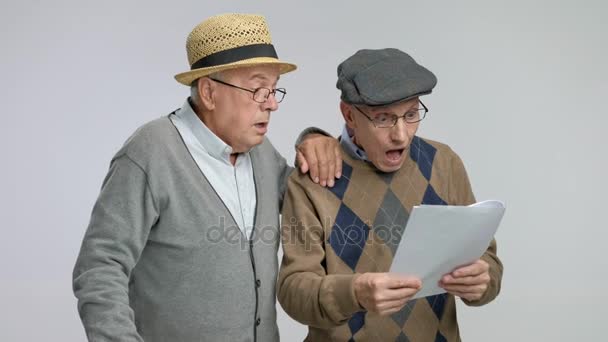 Удивлённые пожилые люди смотрят на документы с недоверием — стоковое видео