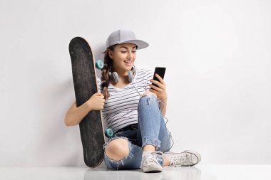 Bir telefonu kullanarak bir kaykay ile genç kız