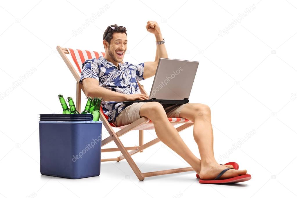 Joyful tourist with a laptop sitting in a deck chair