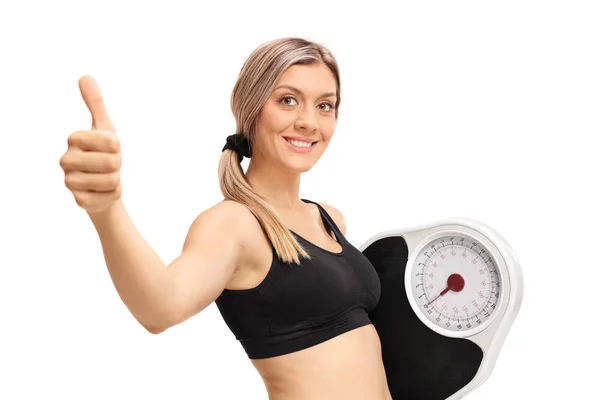 Mujer con una escala de peso haciendo gesto de pulgar hacia arriba —  Fotos de Stock