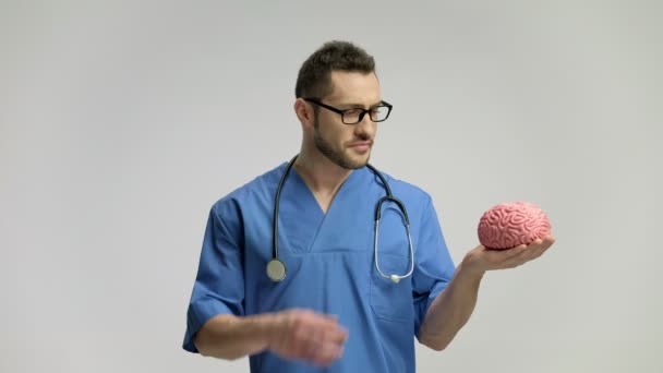 Médico segurando um modelo de cérebro e apontando para cima com o dedo — Vídeo de Stock