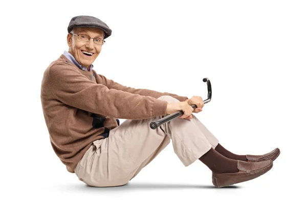 Äldre man med en käpp som sitter på golvet — Stockfoto