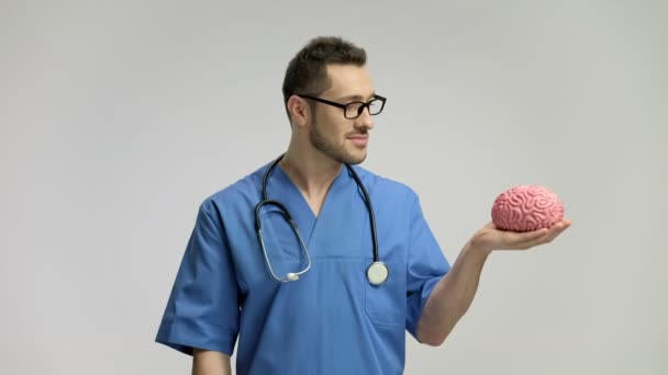 Läkare pekar på en hjärna modell med en pinne och leende — Stockvideo