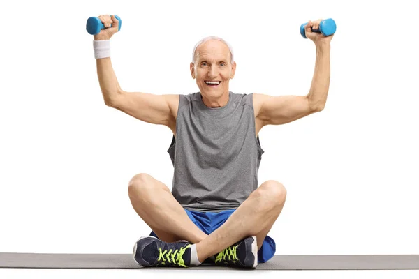 Senior exercising with dumbbells on an exercise mat — Stock Photo, Image