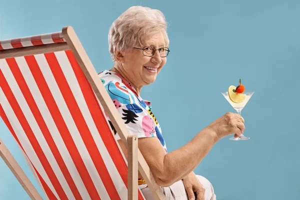 Mujer mayor con un cóctel sentado en una tumbona — Foto de Stock