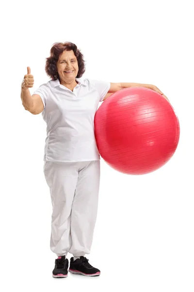 Mujer sosteniendo pilates bola y sosteniendo su pulgar hacia arriba — Foto de Stock