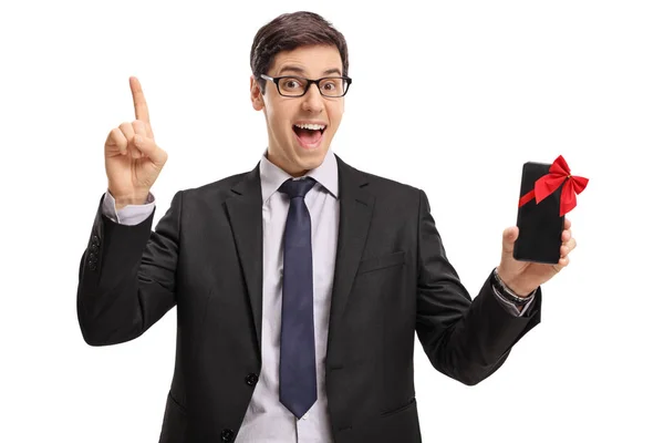 Cheerful businessman showing a phone and pointing up — Stock Photo, Image