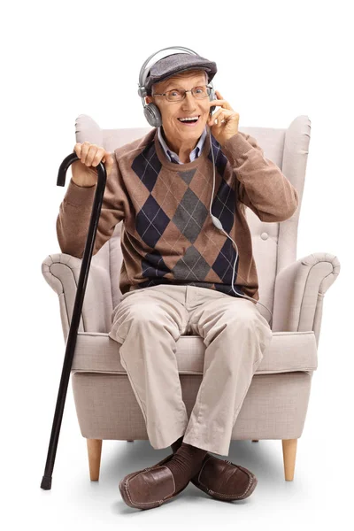 Senior con un par de auriculares y bastón en un sillón — Foto de Stock