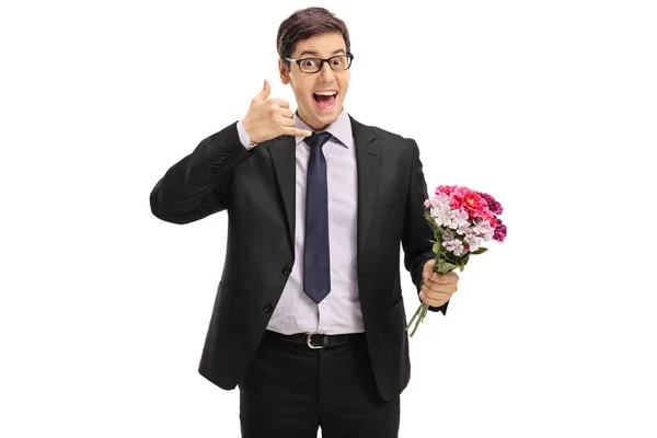 Businessman with flowers making a call me gesture — Stock Photo, Image