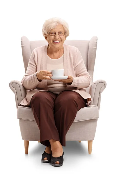 Ηλικιωμένη γυναίκα, κρατώντας ένα φλιτζάνι σε μια πολυθρόνα — Φωτογραφία Αρχείου