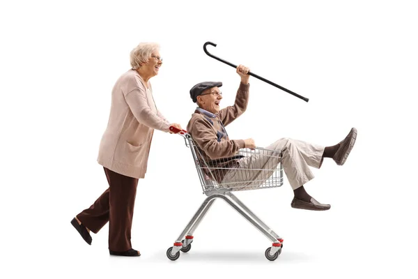 Woman pushing shopping cart with senior riding inside it — Stock Photo, Image