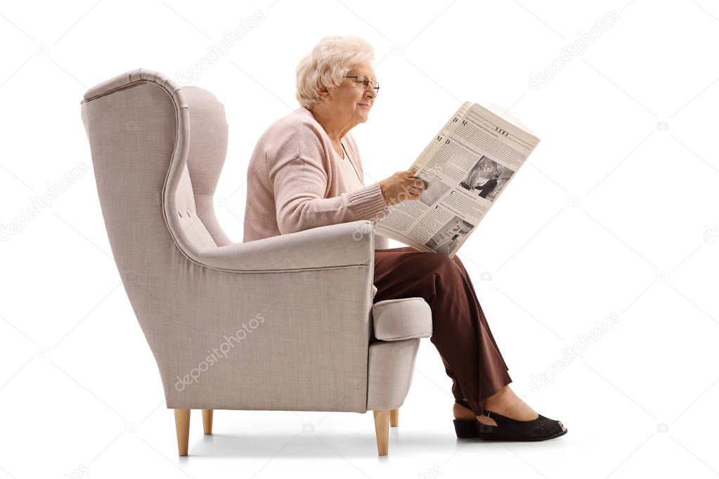 Mature woman in an armchair reading a newspaper