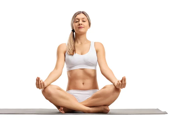 Mujer joven meditando en una esterilla de ejercicio —  Fotos de Stock