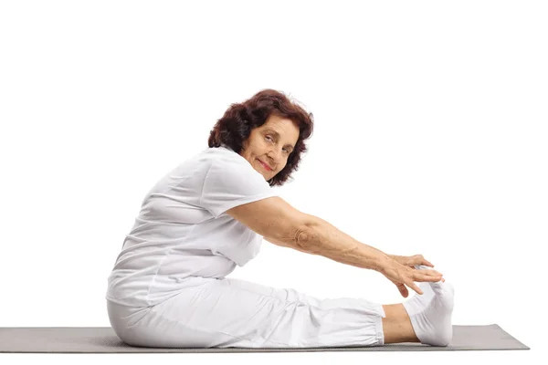 Зрелая женщина растягивается на коврике для упражнений — стоковое фото