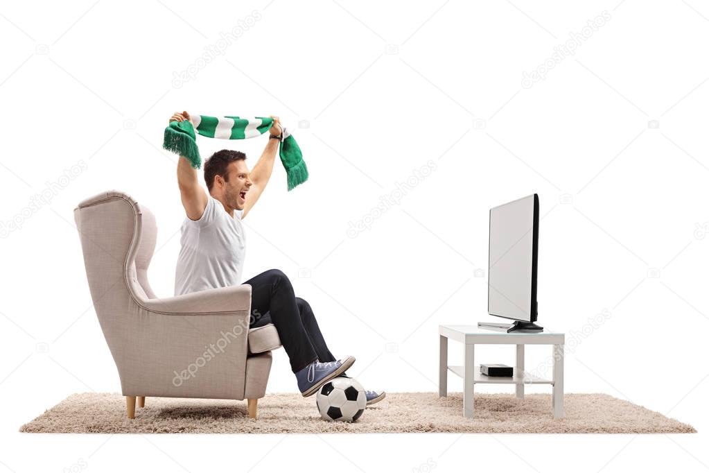 soccer fan with a scarf sitting in an armchair