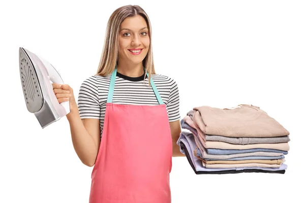 Woman holding iron and pile of ironed and packed clothes — Stock Photo, Image