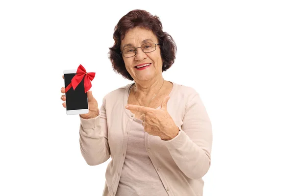 Femme âgée montrant un téléphone et pointant du doigt — Photo