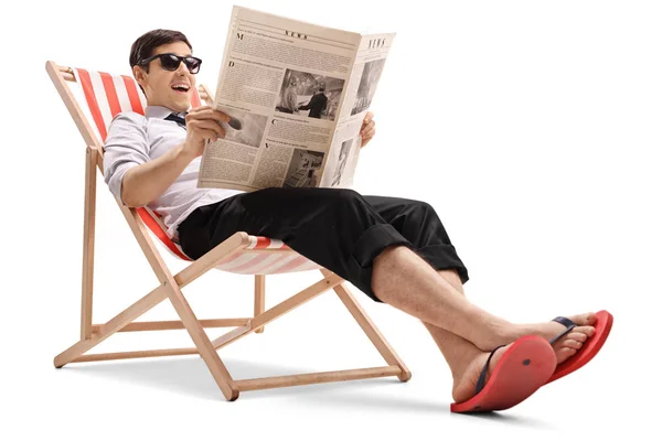 Empresário sentado em uma cadeira de praia e lendo um jornal — Fotografia de Stock