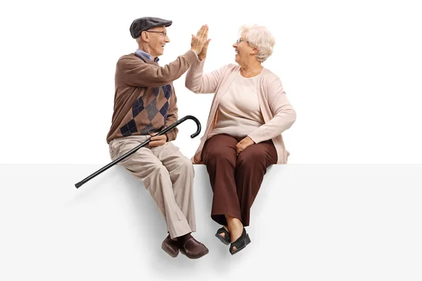 Seniorer som sitter på en panel hög fiving varandra — Stockfoto