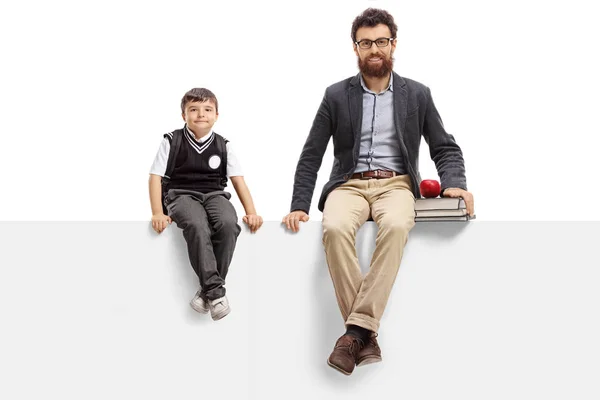 Маленький школьник и учитель, сидящие на панели — стоковое фото